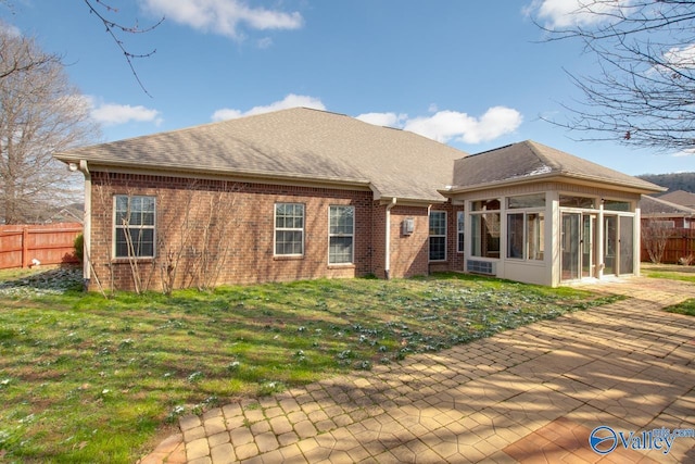 rear view of property with a sunroom, a patio area, fence, and brick siding