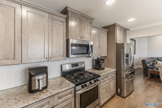 kitchen with backsplash, light wood-type flooring, stainless steel appliances, and light stone countertops