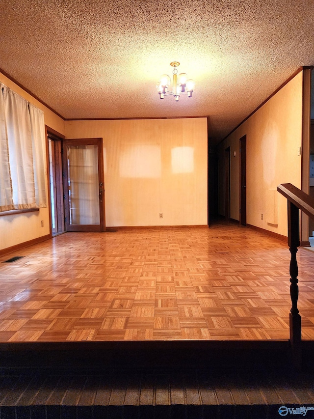 spare room featuring crown molding, a textured ceiling, and a notable chandelier