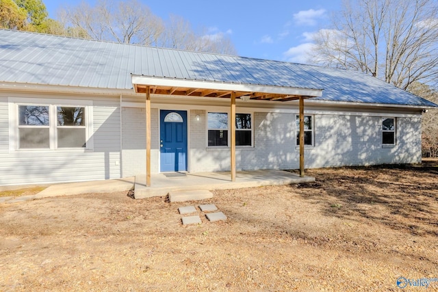 view of front of property featuring a patio area, brick siding, and metal roof