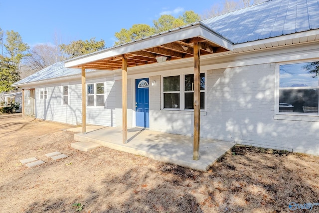 back of property featuring metal roof and brick siding