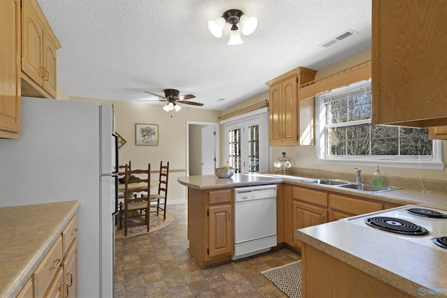 kitchen featuring kitchen peninsula, ceiling fan, white appliances, light brown cabinetry, and sink