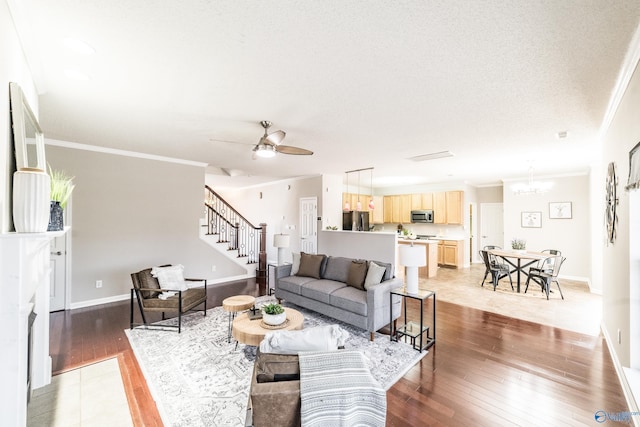 living room featuring crown molding, light wood-style flooring, baseboards, and stairs