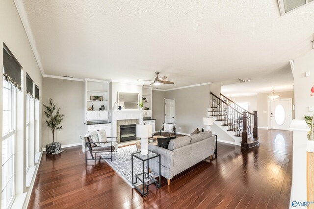 living room featuring dark wood-style flooring, a fireplace, visible vents, a textured ceiling, and stairs