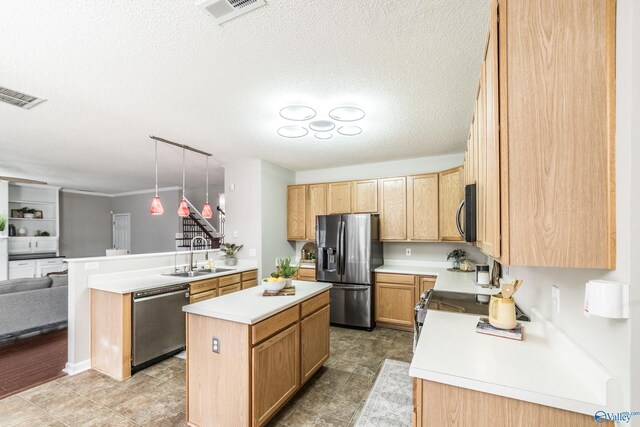 kitchen with a peninsula, appliances with stainless steel finishes, a sink, and visible vents