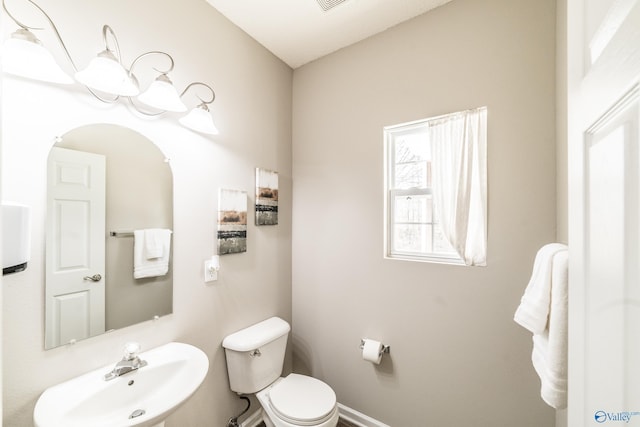 half bathroom with toilet, baseboards, and a sink