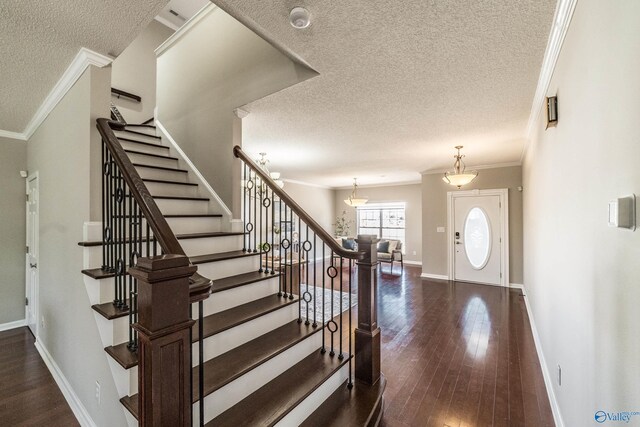 entrance foyer with crown molding, a textured ceiling, baseboards, and dark wood-type flooring