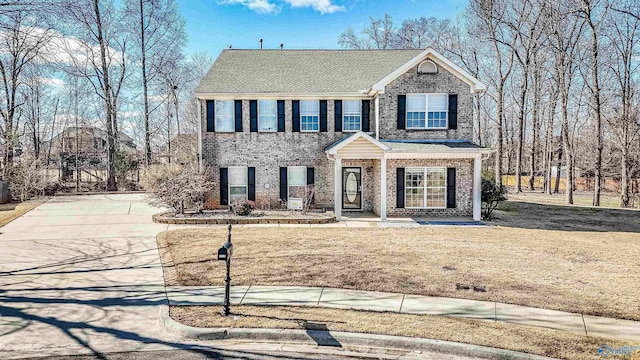 view of front facade featuring a front yard, concrete driveway, brick siding, and roof with shingles