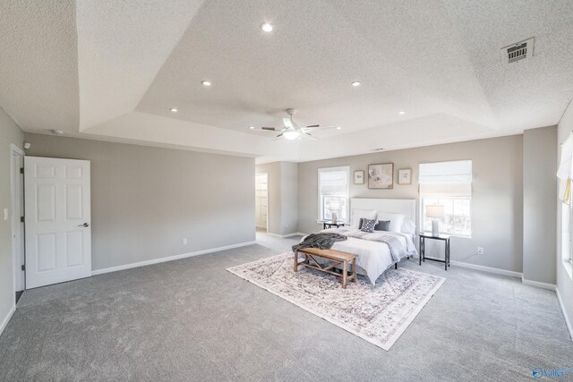 bedroom featuring a raised ceiling, light colored carpet, visible vents, and baseboards