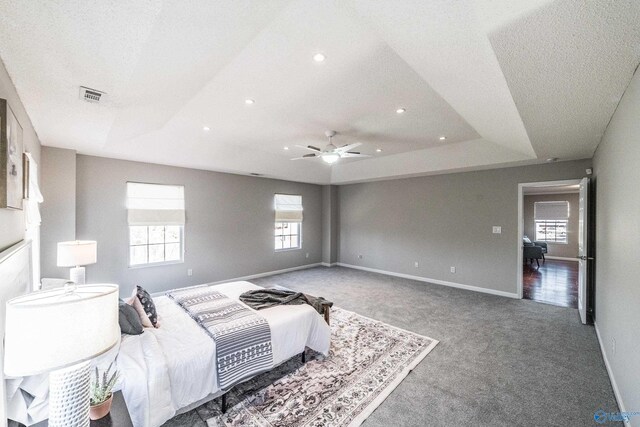 carpeted bedroom featuring recessed lighting, a raised ceiling, visible vents, and baseboards