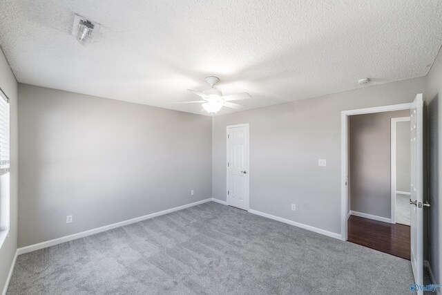 carpeted empty room with ceiling fan, a textured ceiling, and baseboards