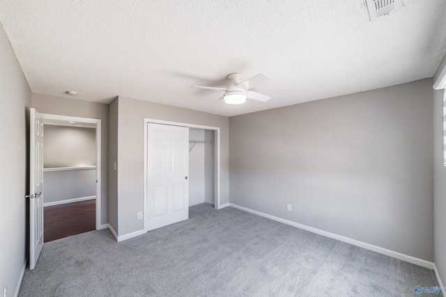 unfurnished bedroom with baseboards, visible vents, carpet, a textured ceiling, and a closet