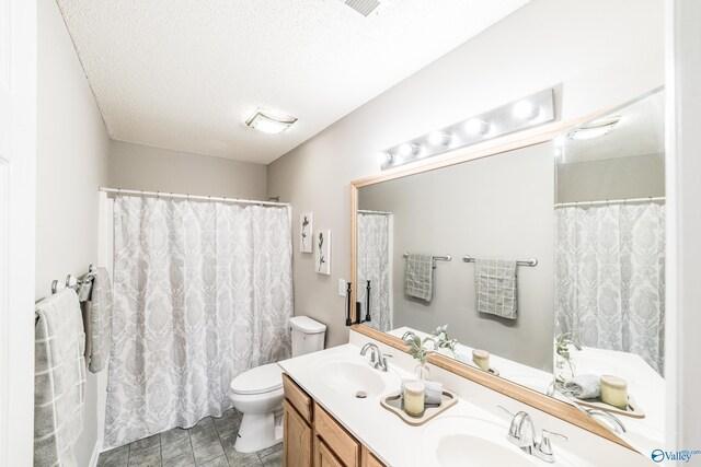 full bath with a sink, a textured ceiling, toilet, and double vanity