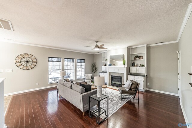 living area with crown molding, a fireplace, dark wood-type flooring, a ceiling fan, and a textured ceiling