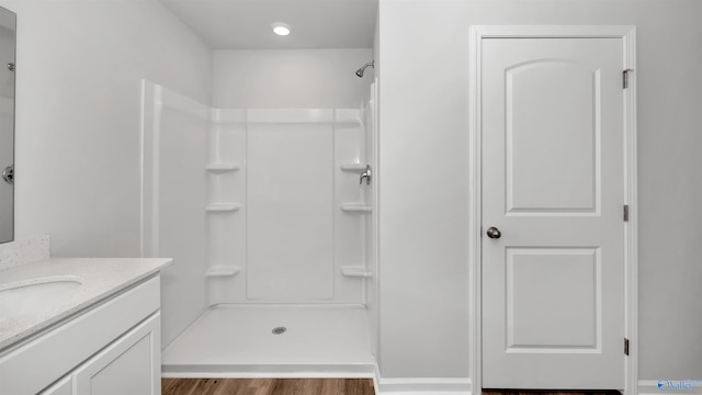 bathroom featuring vanity, wood-type flooring, and walk in shower