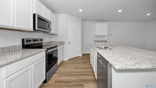 kitchen featuring sink, white cabinetry, an island with sink, stainless steel appliances, and light hardwood / wood-style floors