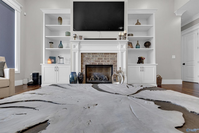 living room featuring a fireplace, built in shelves, and dark hardwood / wood-style floors