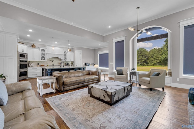 living room with a chandelier, hardwood / wood-style flooring, and crown molding