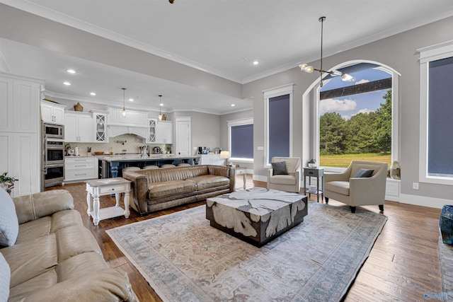 living room with crown molding, wood-type flooring, and an inviting chandelier