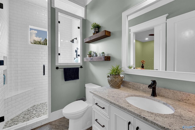 bathroom with toilet, vanity, and a shower with shower door