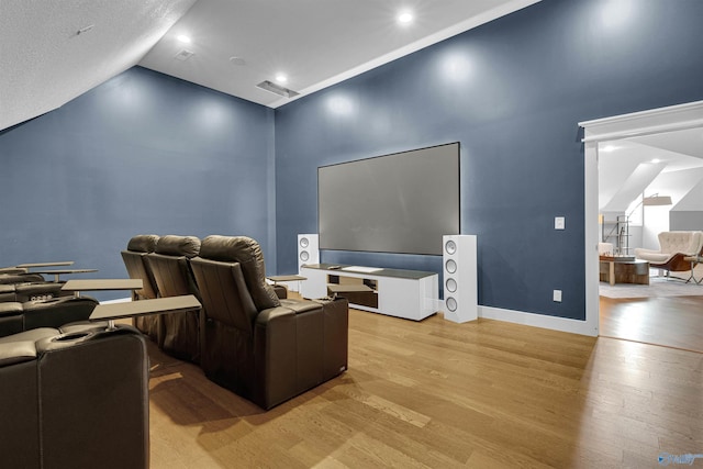 home theater room featuring light wood-type flooring and vaulted ceiling