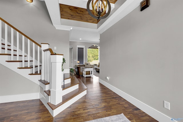 entrance foyer with a notable chandelier, dark wood-type flooring, and a raised ceiling