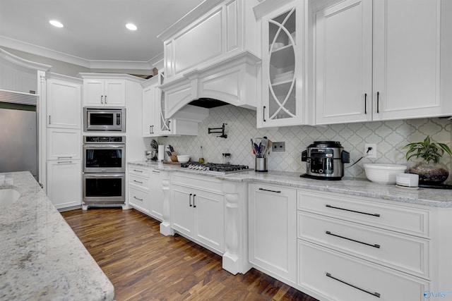 kitchen featuring tasteful backsplash, built in appliances, light stone countertops, white cabinetry, and dark hardwood / wood-style floors