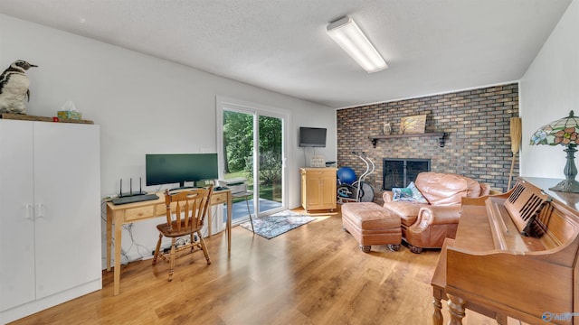 office space with a textured ceiling, a fireplace, and light hardwood / wood-style floors