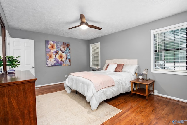 bedroom featuring a textured ceiling, wood finished floors, a ceiling fan, and baseboards