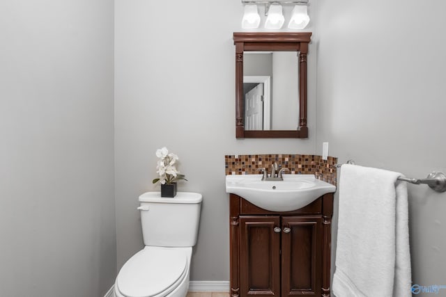 half bath with toilet, vanity, and backsplash