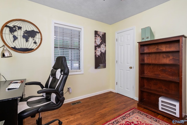office space featuring a textured ceiling, visible vents, wood finished floors, and baseboards