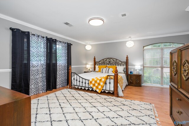 bedroom with visible vents, wood finished floors, and ornamental molding