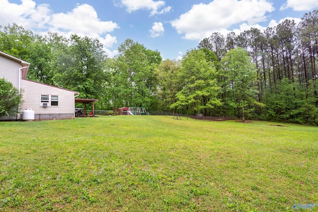 view of yard featuring fence, a carport, and a playground