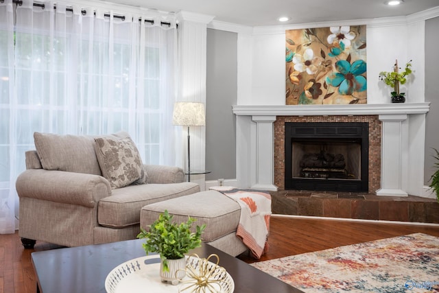 living area featuring a fireplace, wood finished floors, crown molding, and recessed lighting