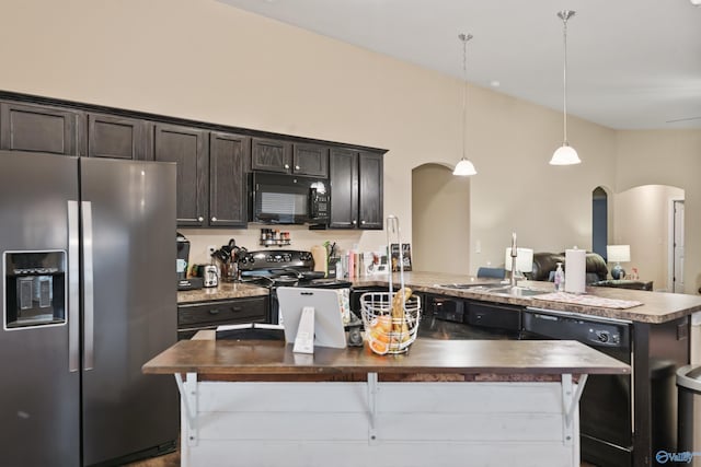 kitchen featuring pendant lighting, sink, dark brown cabinetry, black appliances, and a center island with sink