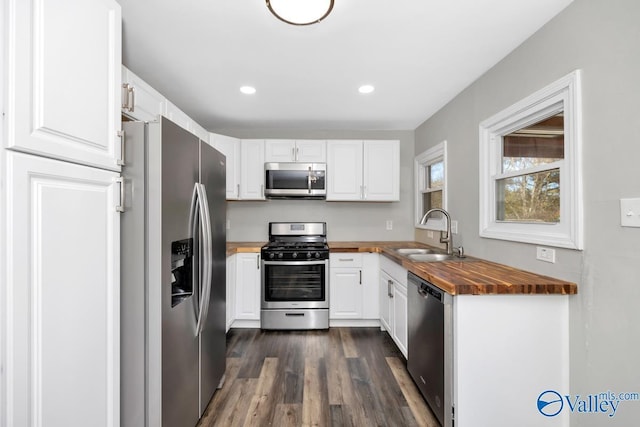 kitchen with white cabinetry, butcher block countertops, stainless steel appliances, and sink