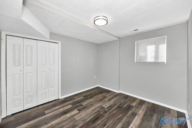 unfurnished bedroom featuring dark hardwood / wood-style flooring, a textured ceiling, and a closet