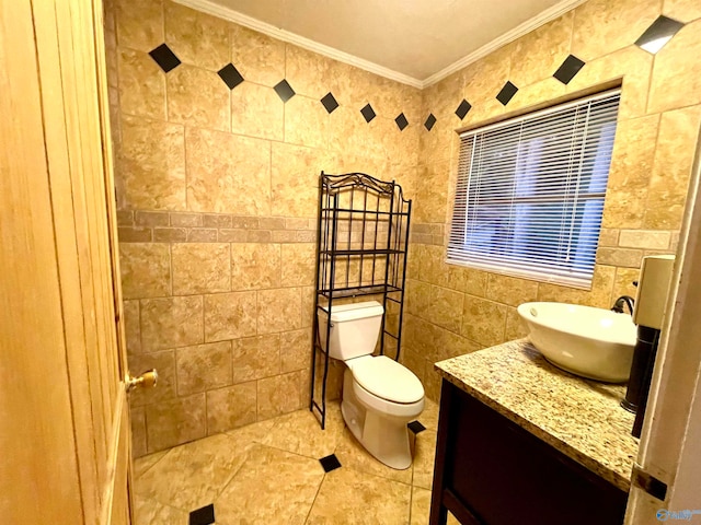 bathroom with tile patterned flooring, toilet, tile walls, vanity, and ornamental molding