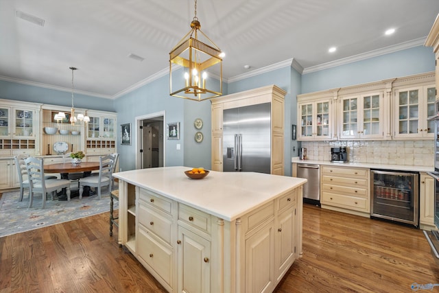 kitchen featuring appliances with stainless steel finishes, hanging light fixtures, a center island, wine cooler, and cream cabinetry