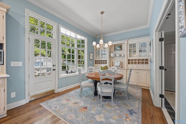 dining area with a notable chandelier, hardwood / wood-style flooring, and ornamental molding