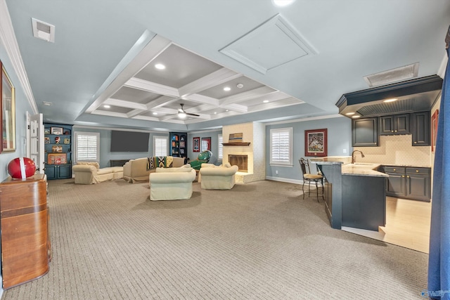 carpeted living room with sink, crown molding, beam ceiling, coffered ceiling, and a fireplace