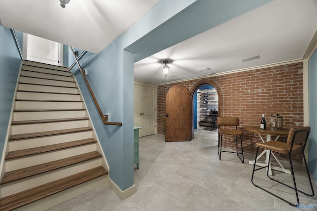 interior space with ornamental molding and brick wall