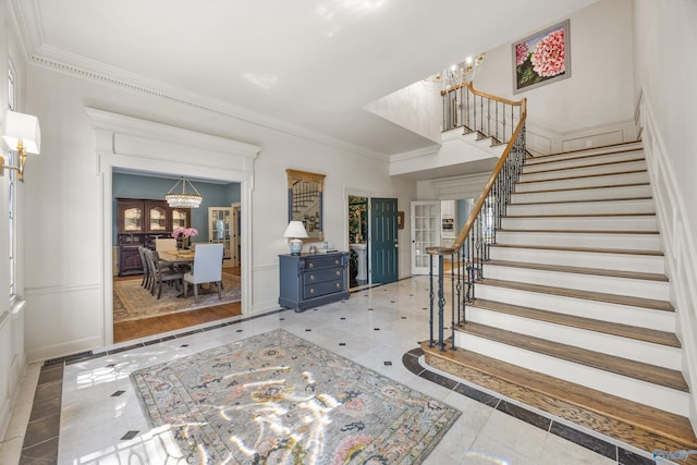 foyer entrance with crown molding, light tile patterned floors, and an inviting chandelier