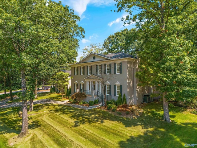 view of front of property with central AC and a front lawn