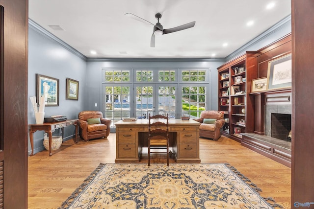 office with a tiled fireplace, light hardwood / wood-style flooring, ornamental molding, and ceiling fan