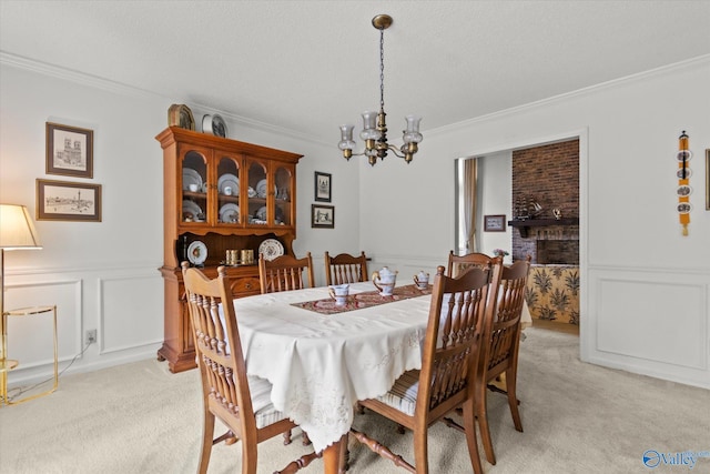 dining area featuring a brick fireplace, light colored carpet, a textured ceiling, a chandelier, and ornamental molding