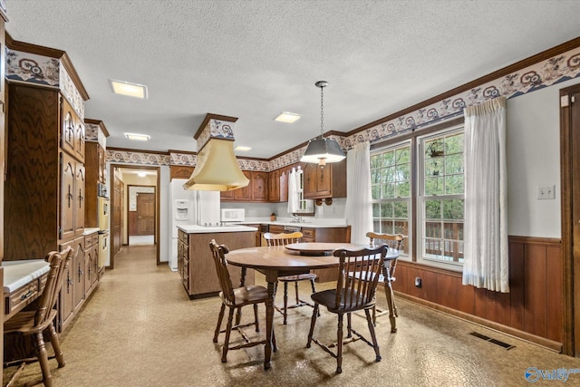 dining area featuring sink, a textured ceiling, light carpet, and ornamental molding