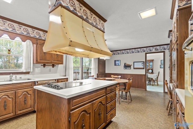 kitchen with premium range hood, a kitchen island, wood walls, sink, and black electric cooktop