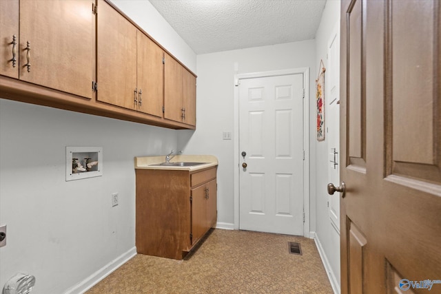 washroom with hookup for a washing machine, a textured ceiling, light carpet, cabinets, and sink