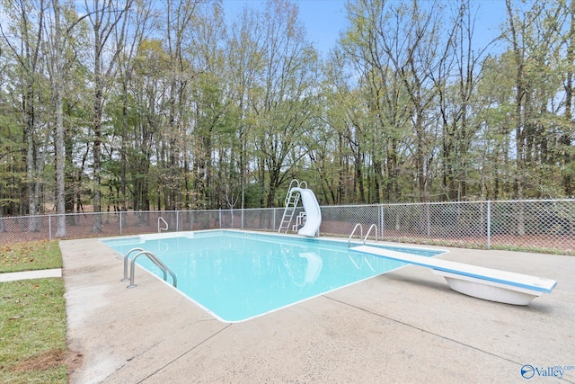 view of swimming pool with a water slide, a patio area, and a diving board